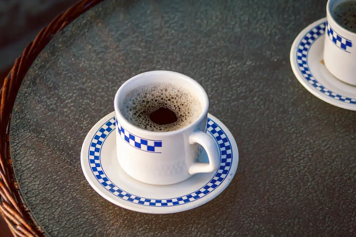 Căni de cafea cu model în carouri albastre pe o masă de sticlă
