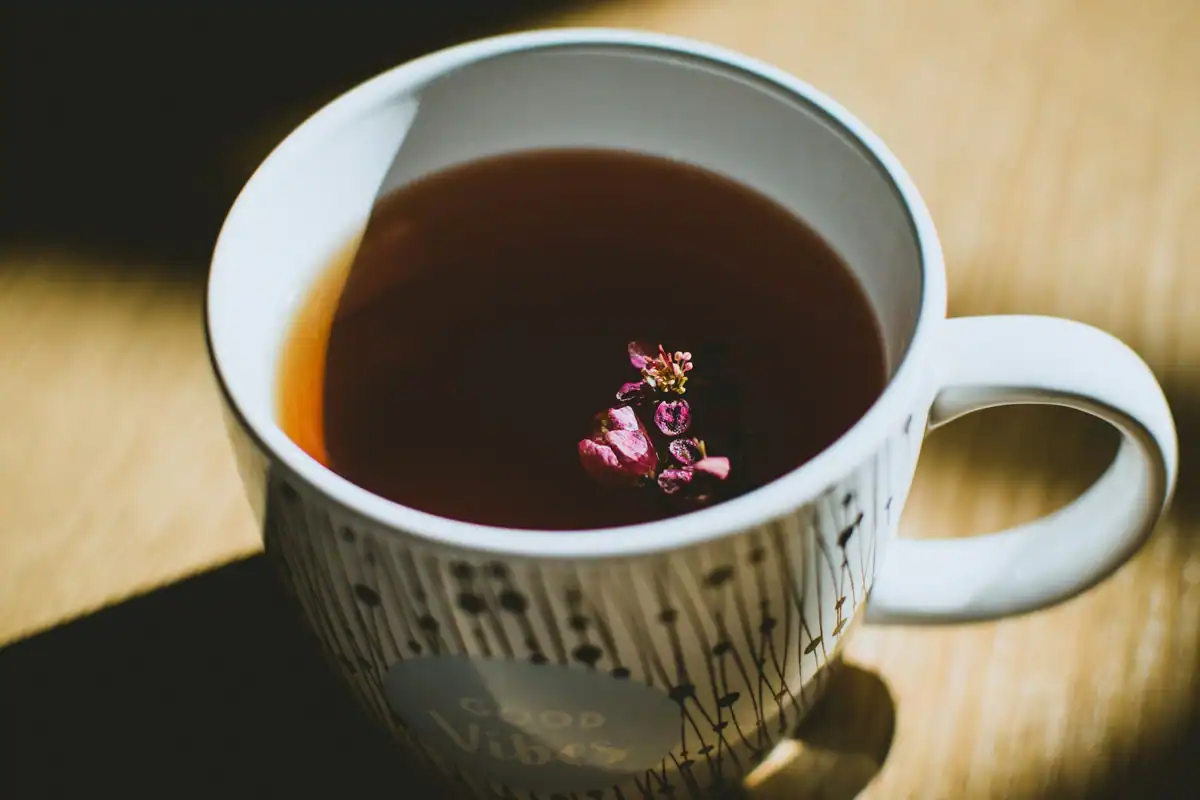 Cană aburindă cu ceai din plante și o floare, alternativă la cafeaua de seară