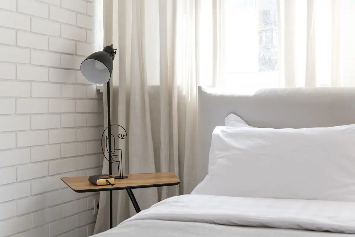 Dormitor minimalist cu pat moale și veioză elegantă, pregătit pentru o noapte odihnitoare