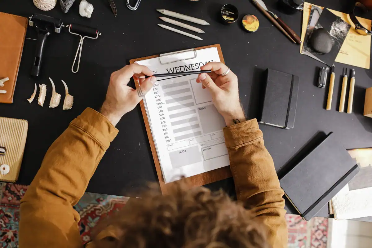 Birou creativ văzut de sus, cu un clipboard pentru planificare, cărți și instrumente de desen
