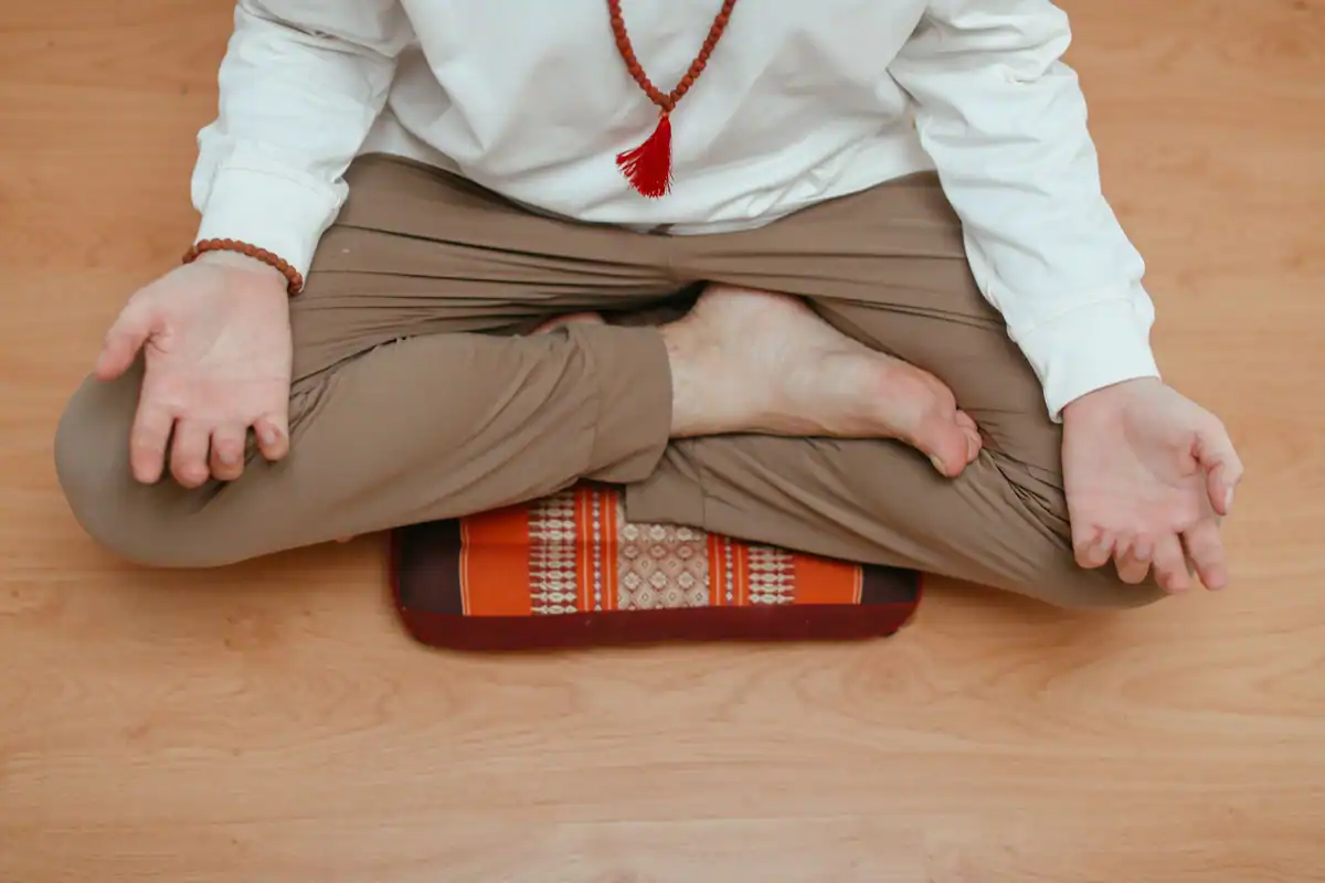 Bărbat care meditează acasă, așezat într-o postură de yoga pe podeaua de lemn