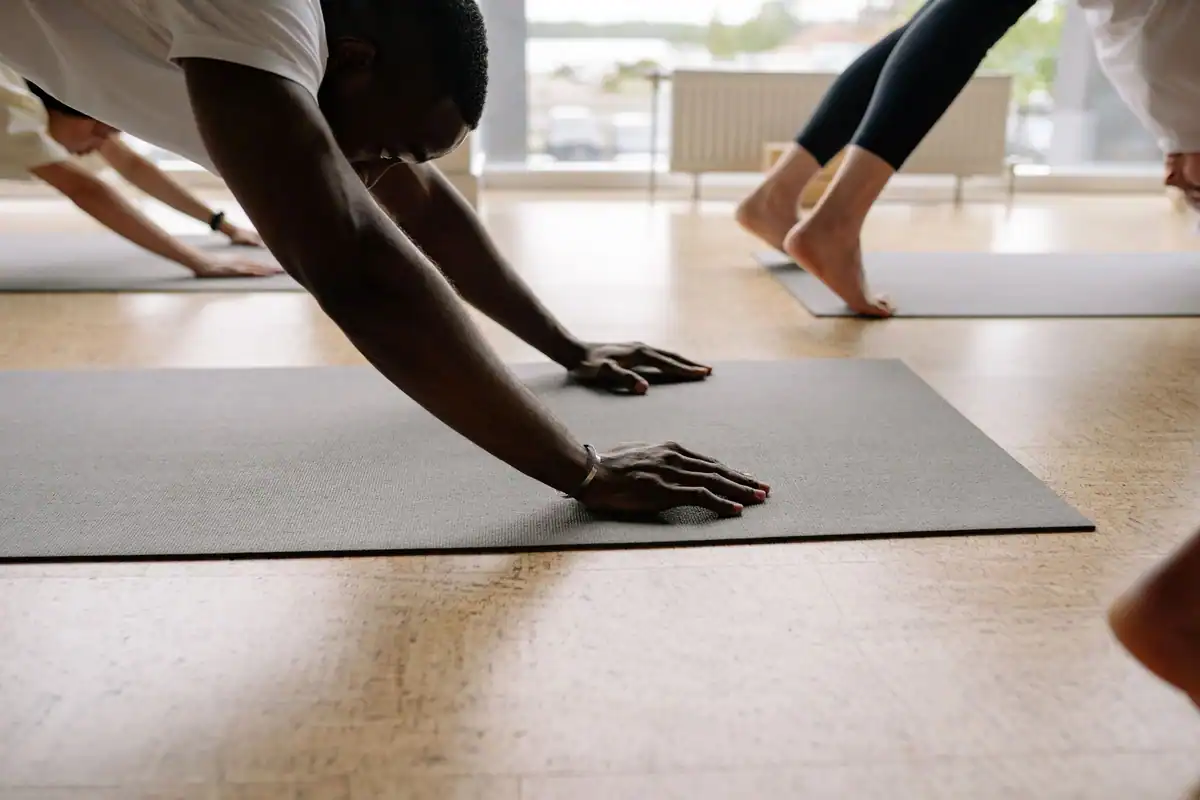 Participanți care fac exerciții de yoga pe saltele într-o sală luminoasă
