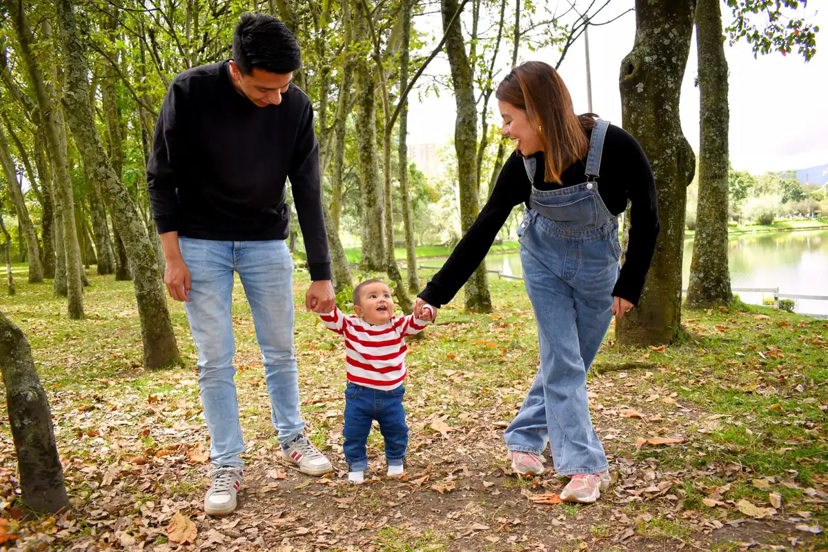 Familie veselă care se plimbă pe sub copaci verzi în parc