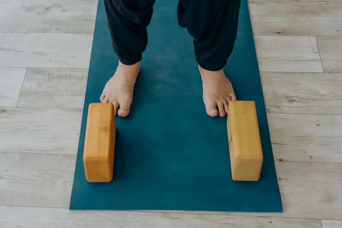 Tălpi pe o saltea de yoga lângă blocuri de lemn, accesorii pentru sprijin