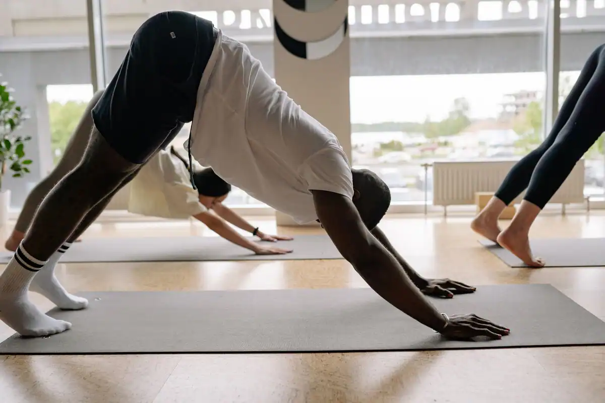 Grup divers de oameni care fac yoga într-o sală cu lumină naturală
